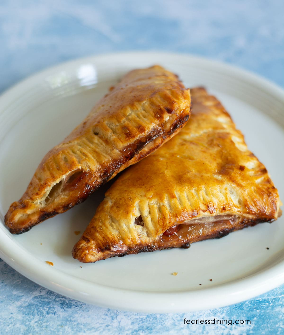 Two baked gluten-free turnovers on a plate.